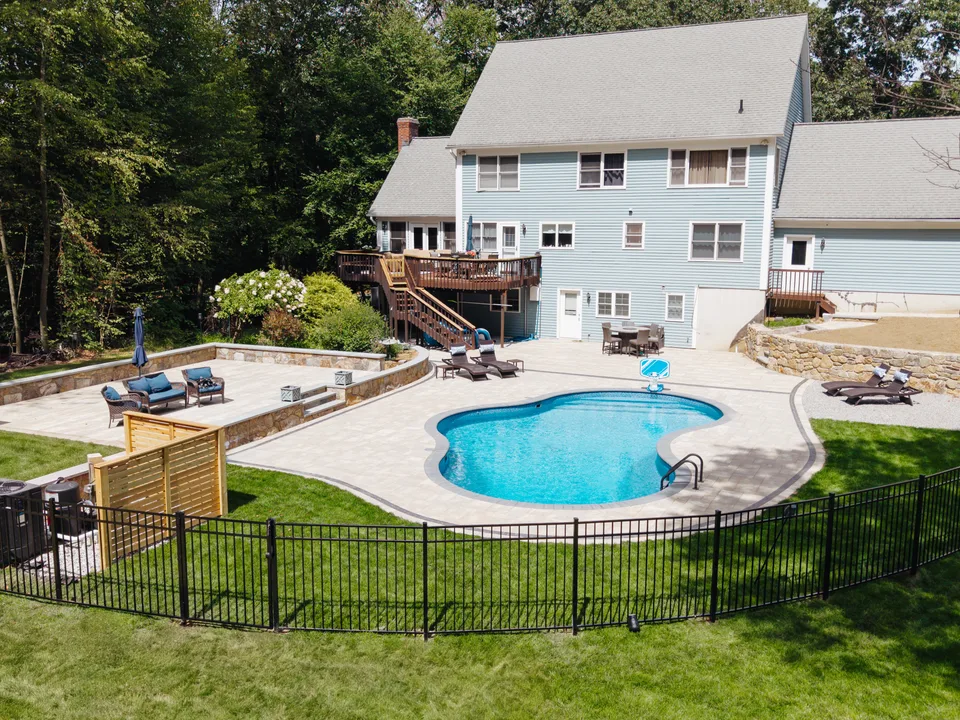 Aerial — the same yard finished: freeform pool, paver deck and sunken stone patio — Exterior Services LLC, Bethel, CT