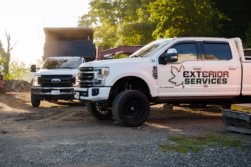 A branded pickup and dump truck in the shop yard at first light — Exterior Services LLC, New Milford, CT