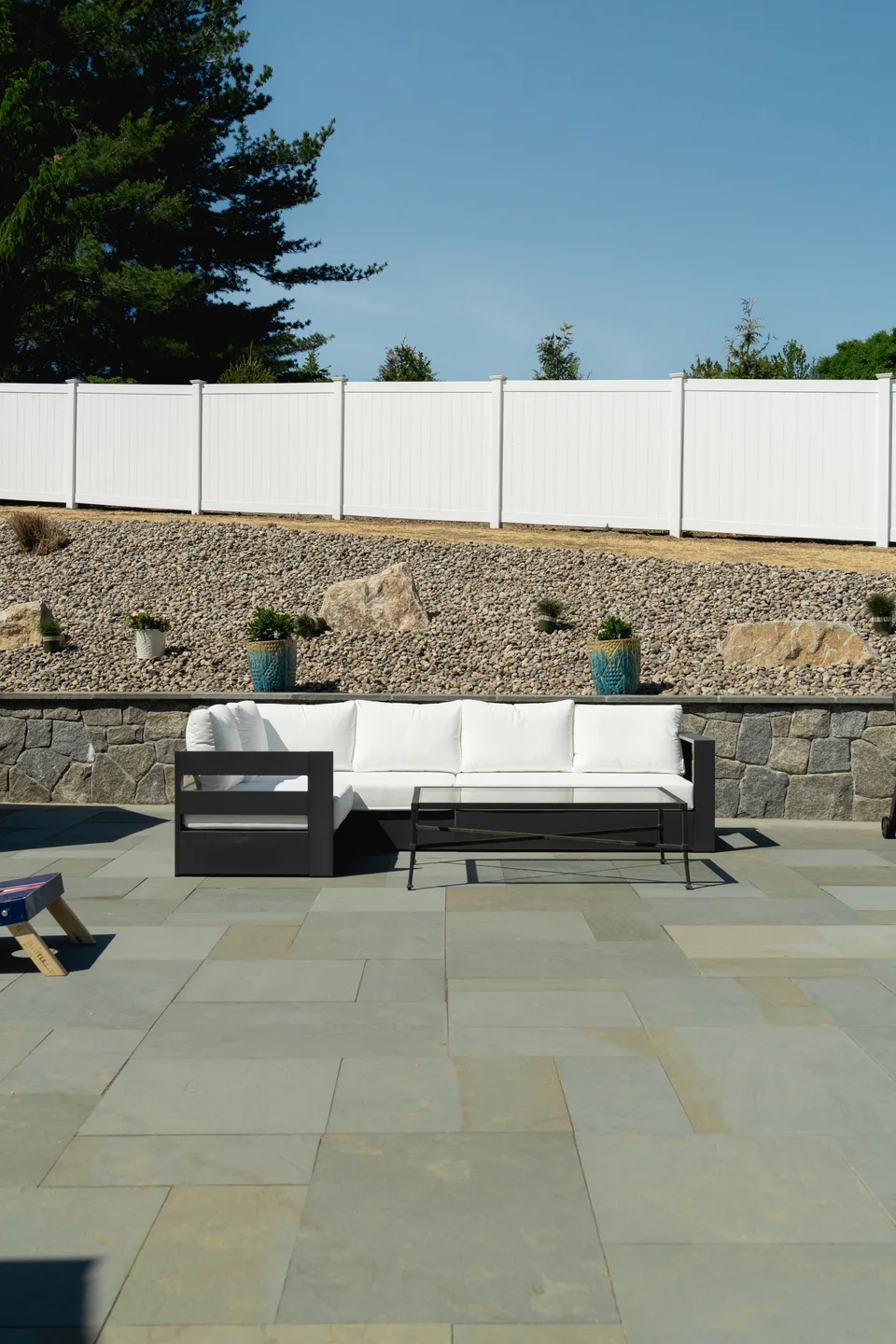 White vinyl privacy fence above a fieldstone wall — Exterior Services LLC, Newtown, CT