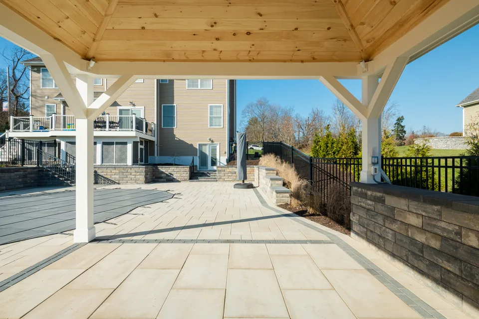 Paver patio seen from under the timber pavilion, seat wall and steps beyond — Exterior Services LLC, Stormville, NY