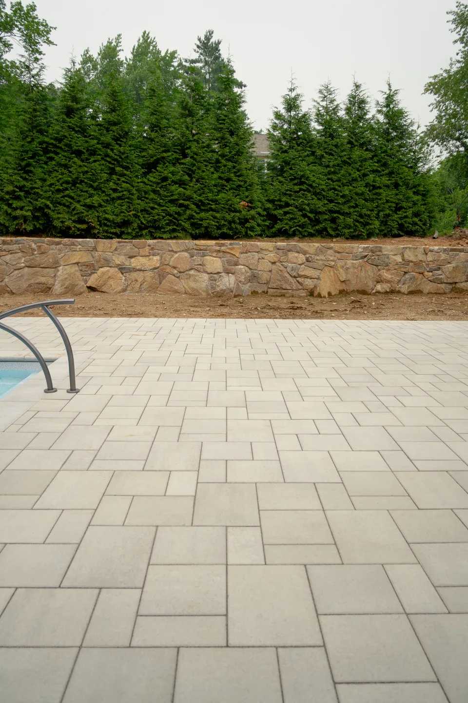 Large-format paver deck against the fieldstone wall — Exterior Services LLC, Danbury, CT