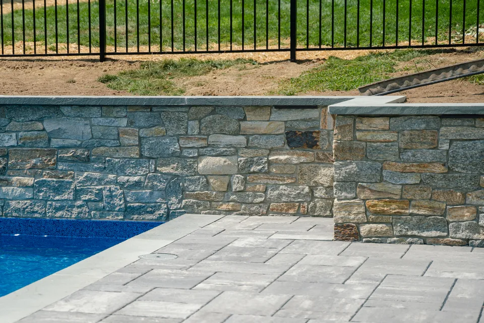 Stone veneer wall meeting the pool deck — Exterior Services LLC, New Milford