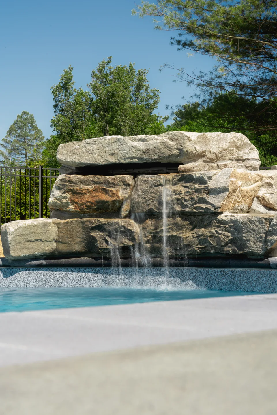 Boulder waterfall spilling into the pool — Exterior Services LLC, Newtown, CT
